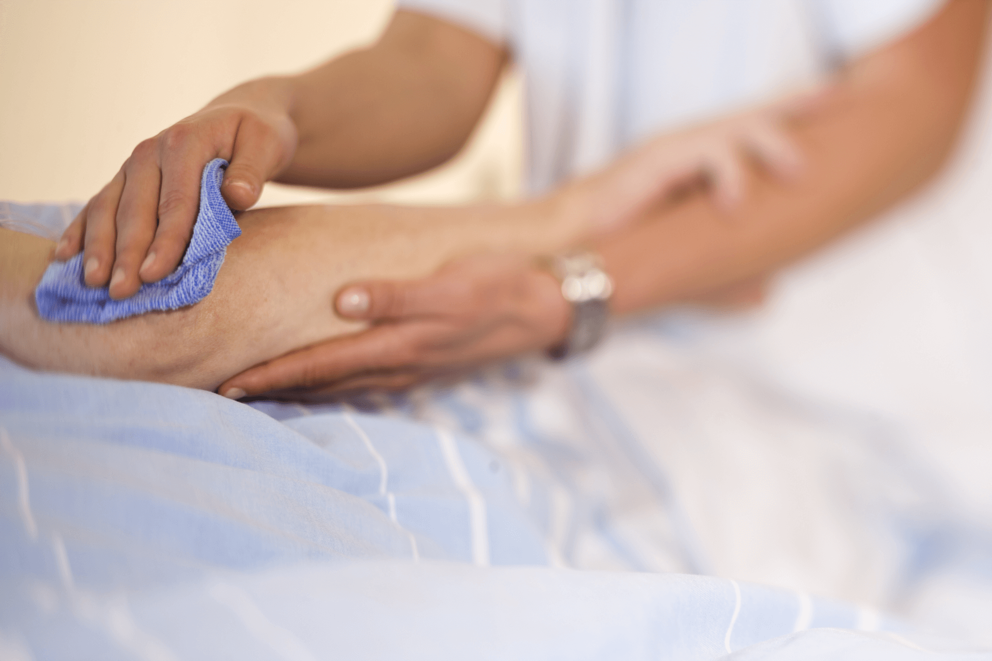Der Arm einer pflegebedürftigen Person wird sanft mit einem Waschlappen gereinigt