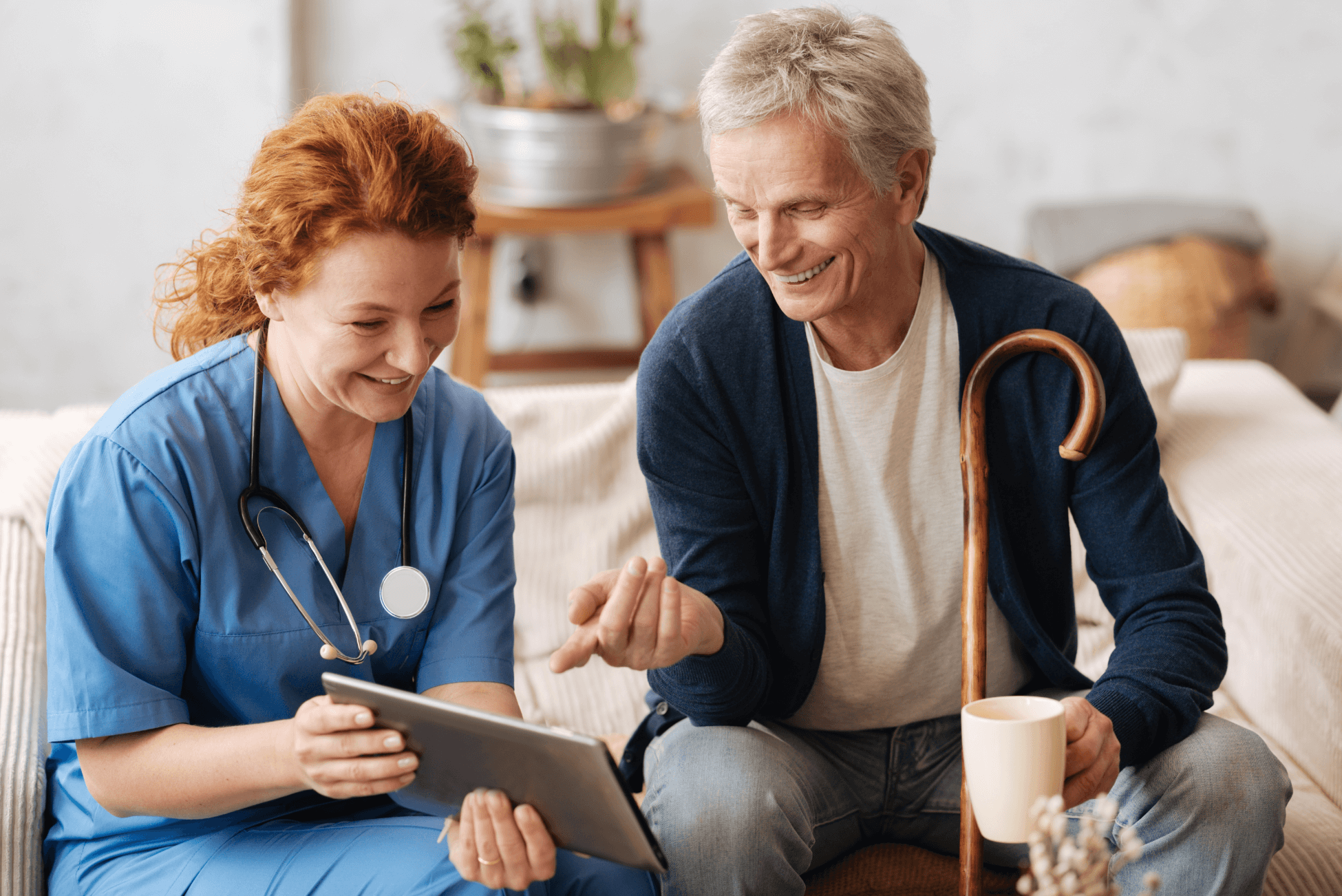 Pflegerin und pflegebedürftige Person schauen gemeinsam in ein Tablet