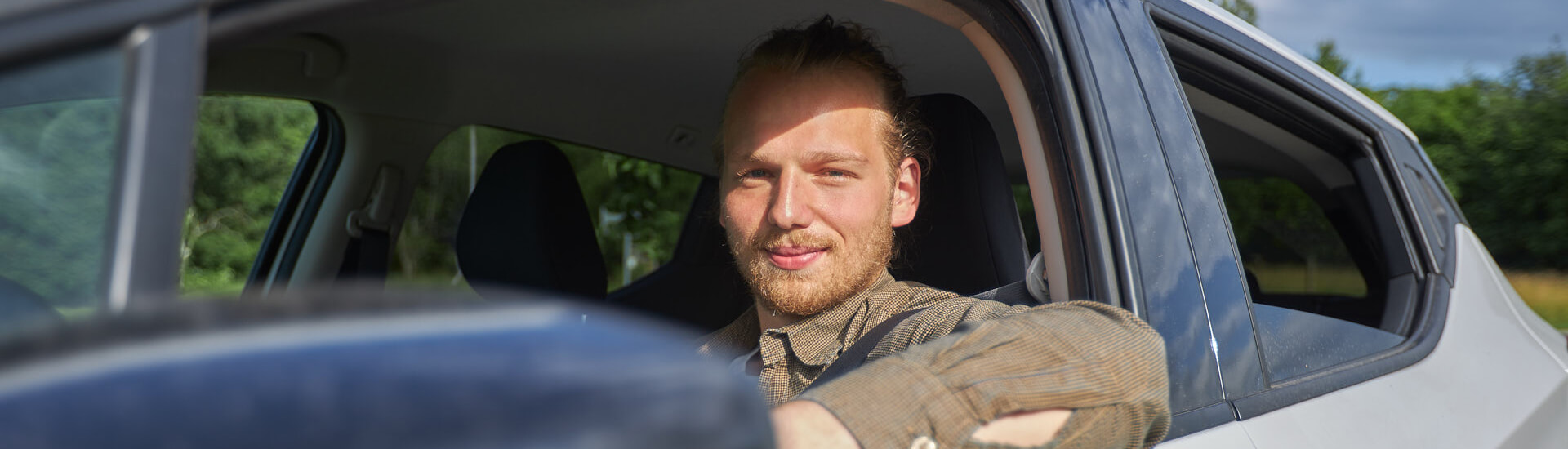 Maximilian Rupp lächelt während einem ambulanten Einsatz aus dem Auto durch das heruntergelassene Fenster