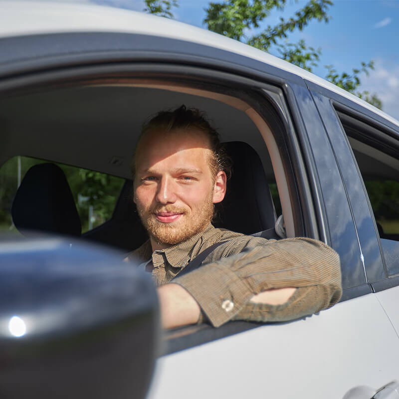 Maximilian Rupp lächelt während einem ambulanten Einsatz aus dem Auto durch das heruntergelassene Fenster