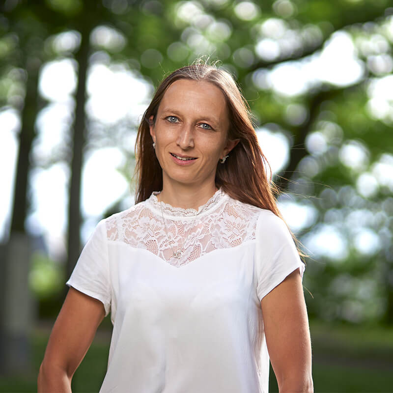 Portrait von Sabine Castro de Manos - sie ist eine Frau mittleren Alters mit langen braunen Haaren