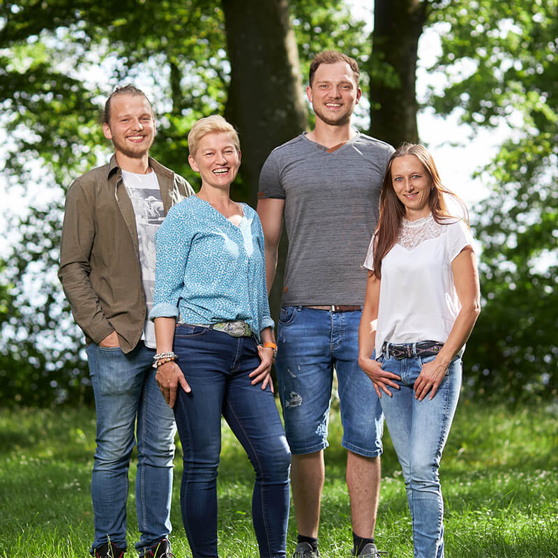 Alle Teammitglieder stehen freundlich auf einer Wiese